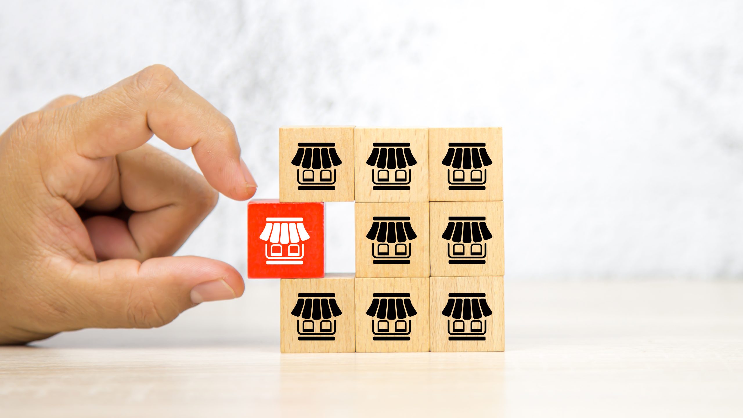 Close-up hand choose wooden block stack with franchise business store icon for franchising to growth branch expansion and business banking loans.