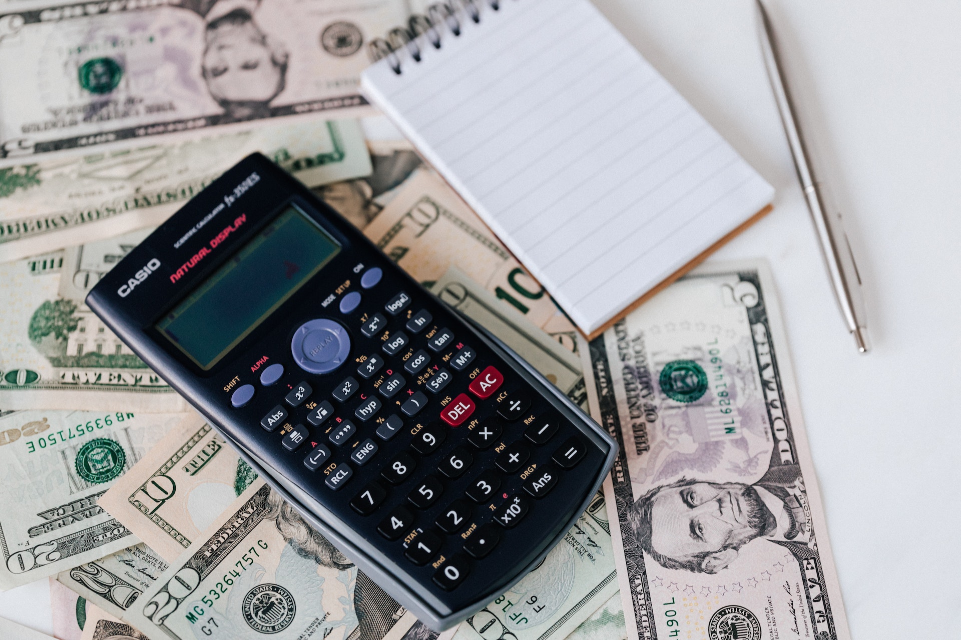A Calculator and a notepad above money bills