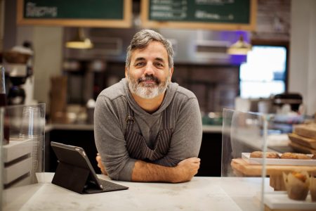 Portrait of smiling male owner with tablet computer on bar count